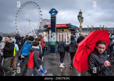 London, UK.  28 March 2024.  UK Weather – Tourists on Westminster Bridge between intermittent downpours as the effects of Storm Nelson are felt in the capital.  The forecast for the Easter Weekend is for more unsettled conditions.  Credit: Stephen Chung / Alamy Live News Stock Photo