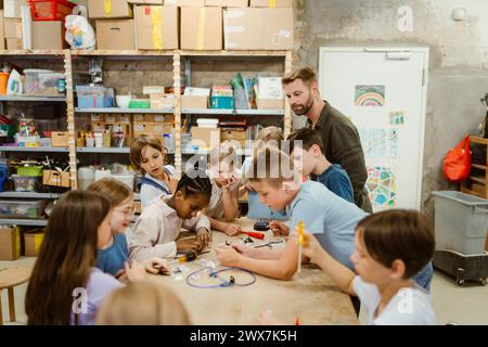 Male and female pupils working on robotics project with teacher in classroom Stock Photo