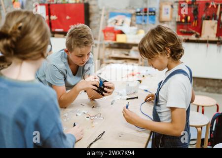 Male and female pupils working on robotics project on table in workshop Stock Photo
