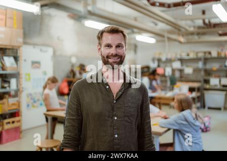 Portrait of smiling male teacher with students in workshop at school Stock Photo