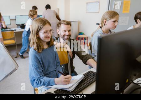 Smiling male teacher with students learning at computer class in school Stock Photo