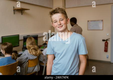 Portrait of smiling male student in computer classroom at school Stock Photo