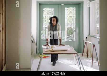 Portrait of confident female architect leaning on table at under construction apartment Stock Photo