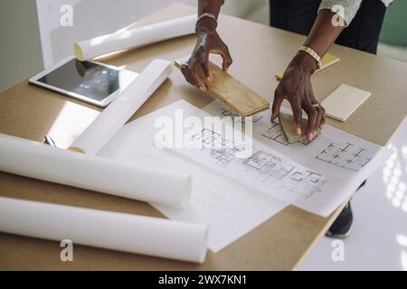 Mature female architect preparing designs modules over blueprint while working at under construction apartment Stock Photo