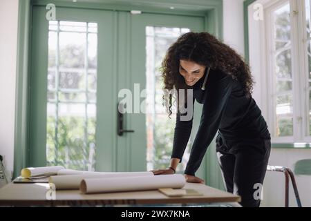 Smiling female construction engineer doing multi-tasking while working at under construction apartment Stock Photo