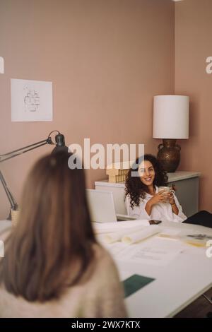 Smiling female architect talking with client during meeting at office Stock Photo