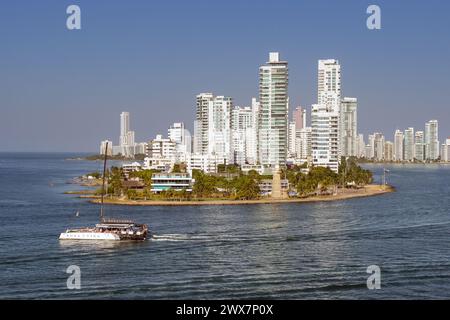 Cartagena, Colombia - 24 January 2024: Yacht passing the Naval Club and lighthouse at the entrance to the city's port Stock Photo
