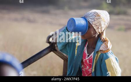 Junge Frau, Maedchen trinkt aus einem Plastikbecher Wasser in der Gemeinde Maraban Dare im Bundesstaat Plateau in Nigeria, 07.02.2024. Maraban Dare Ni Stock Photo