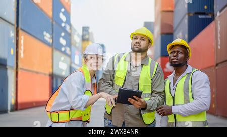 Three workers in front of containers at an industrial site Stock Photo