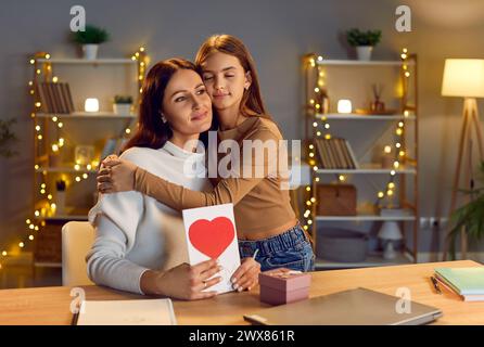 Young happy teen girl congratulating her mother on holiday at home with gift. Stock Photo