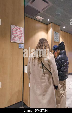 Nueva York, USA - March 27, 2024: Image shows customers forming a queue to pay in a modern store. A clerk can be seen in the background, indicating an Stock Photo