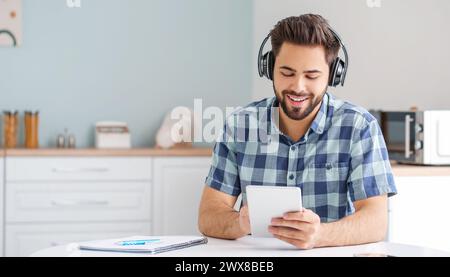 Young man using tablet computer and headphones at home Stock Photo