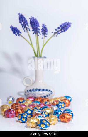 A creative arts vase holds electric blue flower next to easter eggs Stock Photo