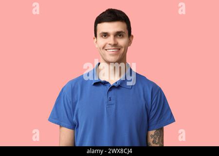 Handsome young man in stylish blue t-shirt on pink background, closeup Stock Photo