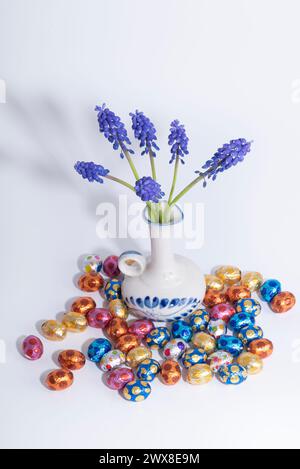 A creative arts vase holds electric blue flower next to easter eggs Stock Photo