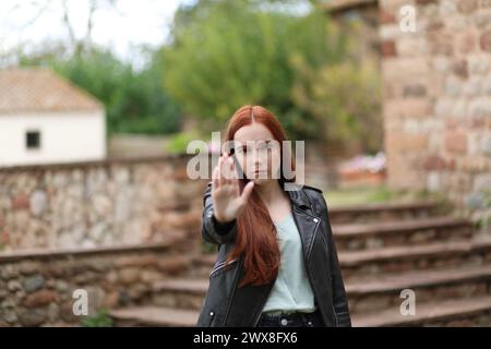 Woman with serious face makes the stop gesture with her hand raising her arm Stock Photo