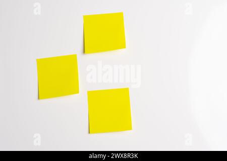 Three blank yellow sticky notes posted on an isolated white background Stock Photo