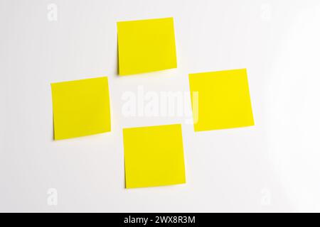 Four blank yellow sticky notes posted on an isolated white background Stock Photo