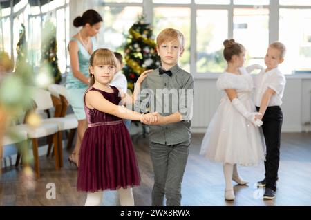 Little children in festive clothes dance foxtrot dance while celebrating Christmas Stock Photo