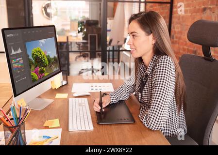 Graphic designer woman working in office, using photo editor software Stock Photo