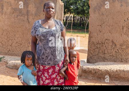 african family with three children standing in front of the mud house, african village life Stock Photo
