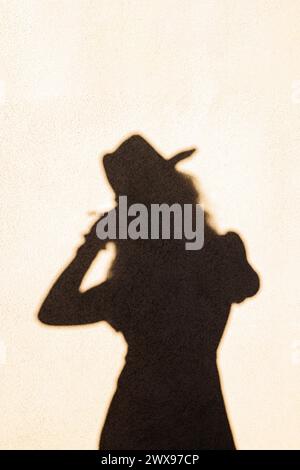 Abstract Shadow of a woman wearing hat reflection on the wall in sunset light Stock Photo