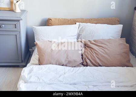 Close up of soft orthopedic mattress with pillows, blanket, bed linen, bedding items, gray chest of drawers. Background, backdrop with copy space. Template, mockup for your design. Stock Photo