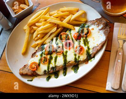 Beef steak with mozzarella, tomatoes and pesto served with fries Stock Photo