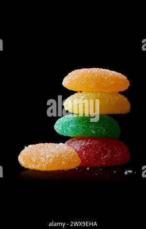 jujubes, fruit flavored colorful gummy chewy candy confectionery with elongated shaped stacked isolated black background with copy space Stock Photo