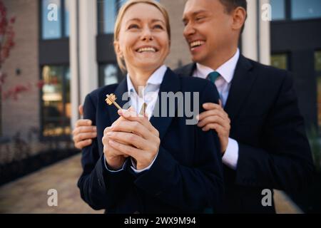 Man embraces woman who holds keys in hands Stock Photo
