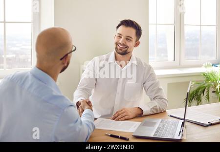Smiling businessman shaking hand of partner or colleague at meeting Stock Photo