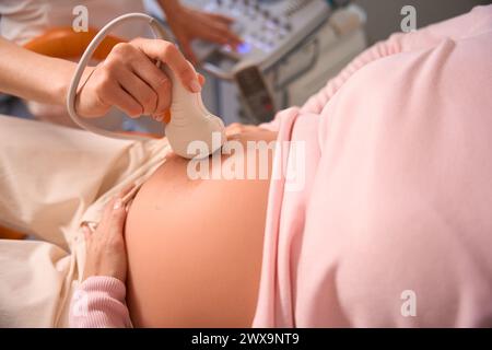 Professional doctor performs procedure of ultrasound of fetus of pregnant female Stock Photo