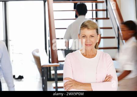 Woman, CEO and busy office with arms and smile for work, leader or management or senior. Female person, boss and corporate or mature with experience Stock Photo