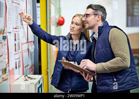 People, business and checking schedule with board in warehouse with calendar for order details. Man, woman and together with checklist or clipboard Stock Photo