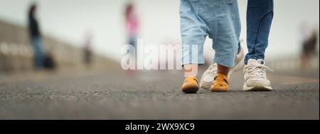 close up leg of infant baby walking on a path with mother helping Stock Photo