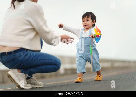 infant baby learn walking first step on a pathway with mother helping Stock Photo