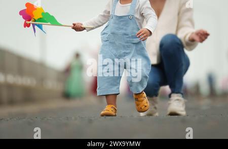close up leg of infant baby walking on a path with mother helping Stock Photo