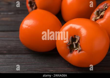 Delicious ripe persimmons on dark wooden table, closeup Stock Photo