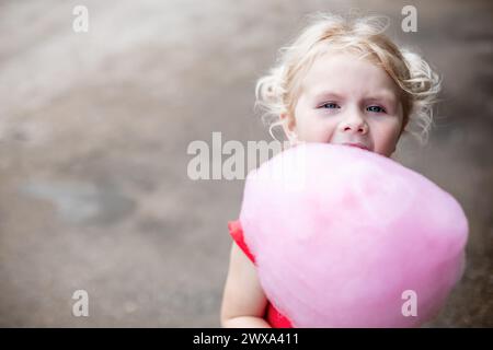 Young girl holding giant pink cotton candy at carnival Stock Photo