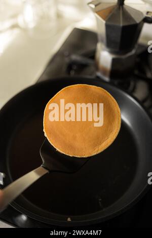 Frying pancakes, flipping with spatula on frying pan. Kitchen cooking Stock Photo