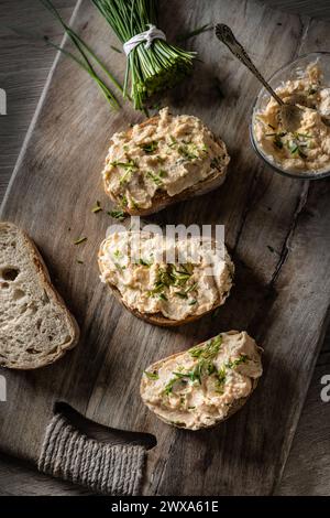 Close-up of bread slice with traditional Slovak bryndza spread made of sheep cheese with freshly cut chives placed on rustic wood. Stock Photo