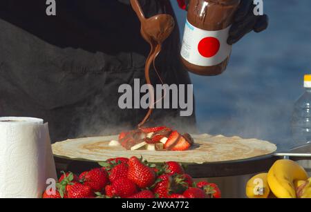The midsection body of a chef preparing sweet fruit crepes, French pancakes at farmers market stall in Prague Naplavka, Czech Republic Stock Photo