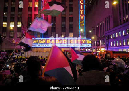 Pro-Palestine demonstrators rally waving Palestinian flags. Pro-Palestine demonstrators rallied outside of Radio City Music Hall in Manhattan, New York City where a presidential campaign fundraising event for Joe Biden attended by Biden, Barack Obama and Bill Clinton took place. Demonstrators condemned the Israel Defense Forces' military operations in Gaza and the United States government for arming the IDF. On Monday, the United Nations Security Council adopted a resolution demanding a ceasefire between the IDF and Hamas until the end of Ramadan. The United States abstained from the vote. Sin Stock Photo