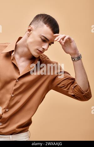 Portrait of young handsome man in beige shirt looking down on peachy beige background Stock Photo