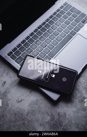 Smartphone resting on laptop with secure access to user's personal information on screen. Sign in or register with username and password. Stock Photo