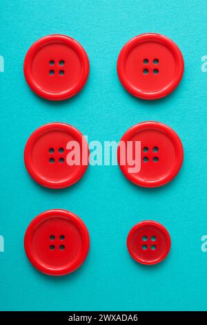 Close-up of six red buttons of different sizes on a green surface Stock Photo