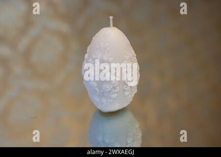White easter egg soy wax candle. Mirror background Stock Photo