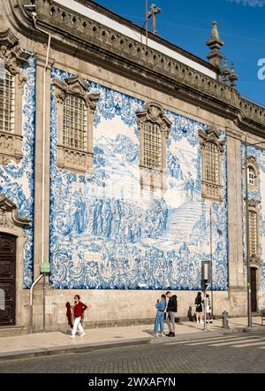 People pass by the facade of Igreja do Carmo church, adorned with intricate blue and white tiles, Porto, Portugal Stock Photo