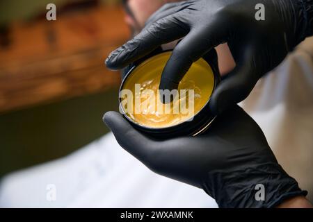 Hairdresser in black gloves using styling tool for making hairdo Stock Photo