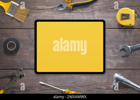 Tablet mockup for app promotion, surrounded by tools on wooden table. Perfect for showcasing your app. Top view, flat lay composition. DIY concept Stock Photo